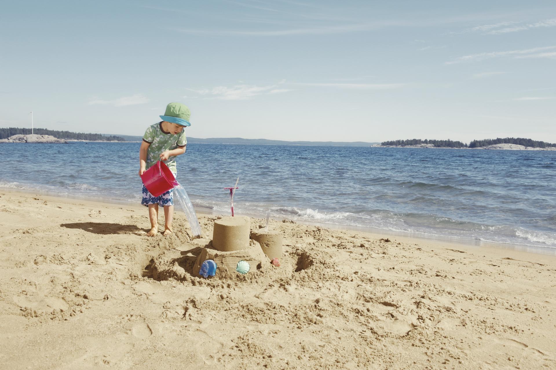 Ett barn bygger sandslott på stranden