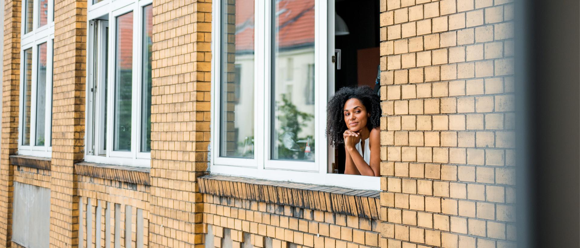 En kvinna står vid fönstret och tittar utåt