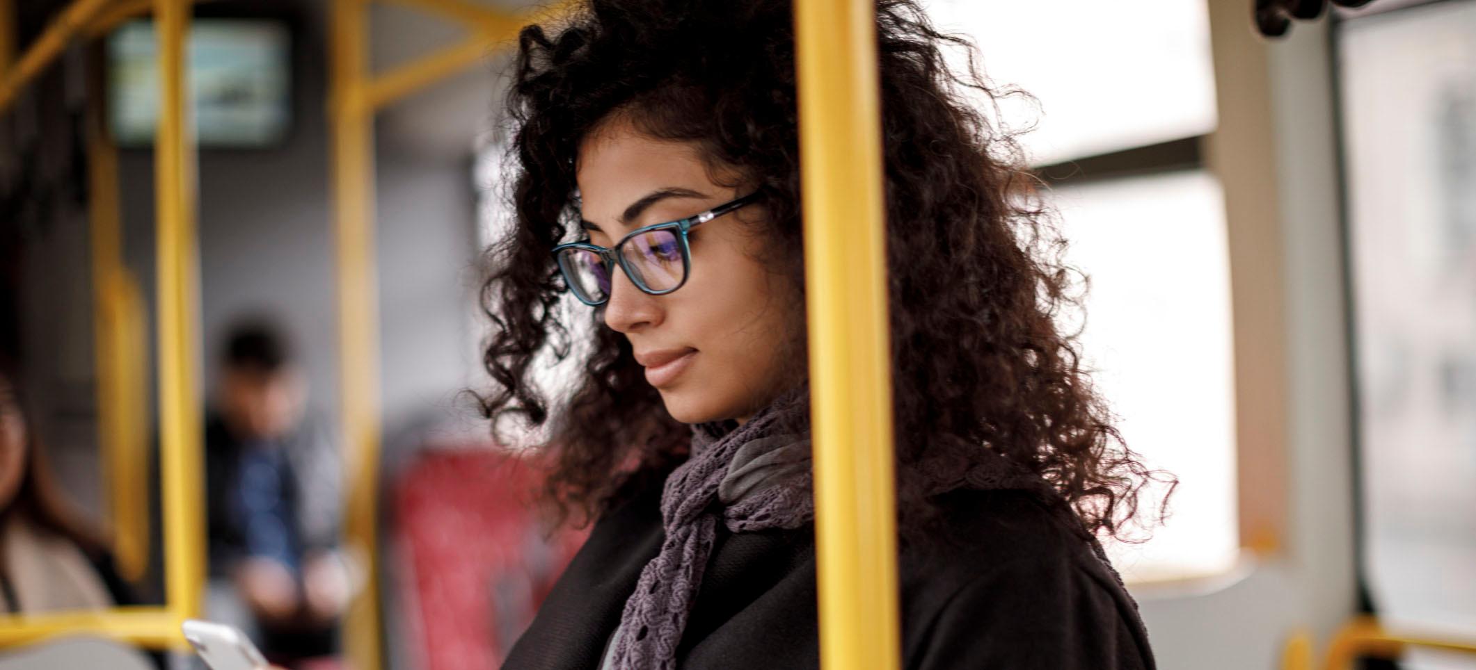 Kvinna står med mobil på buss