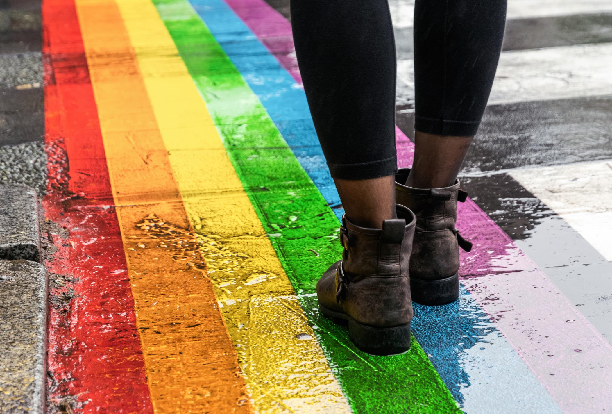 Närbild på fötter mot en regnbågsmålad gata
