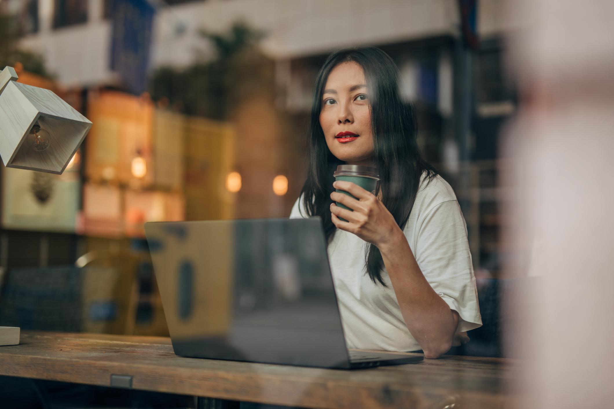 En kvinna sitter och jobbar på ett café 