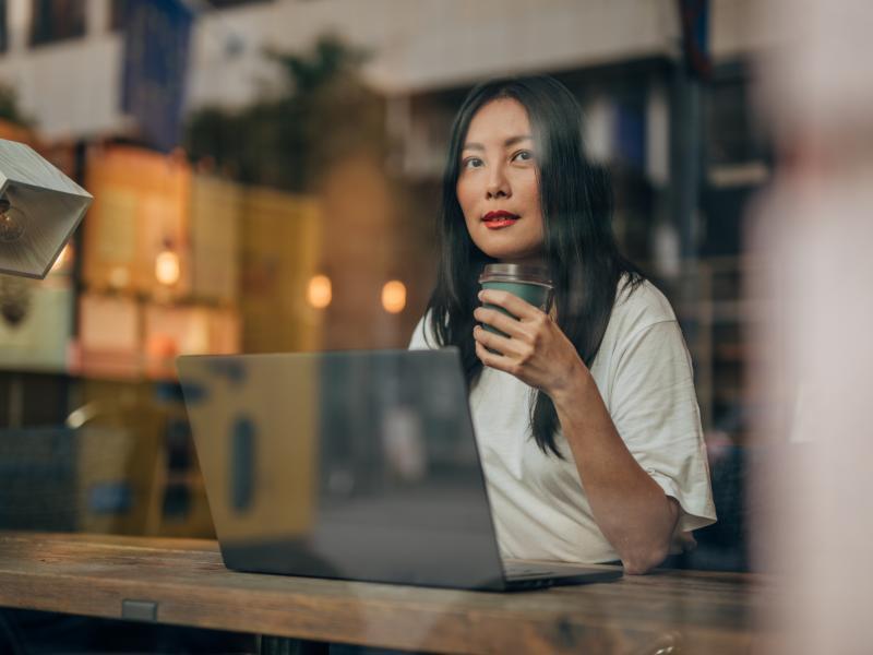 En kvinna sitter och jobbar på ett café 