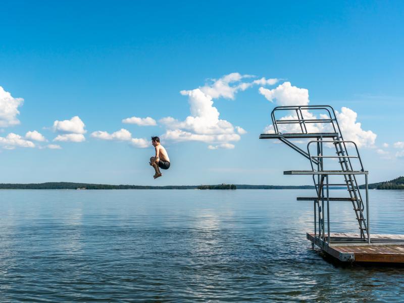 En man hoppar i vattnet från en brygga